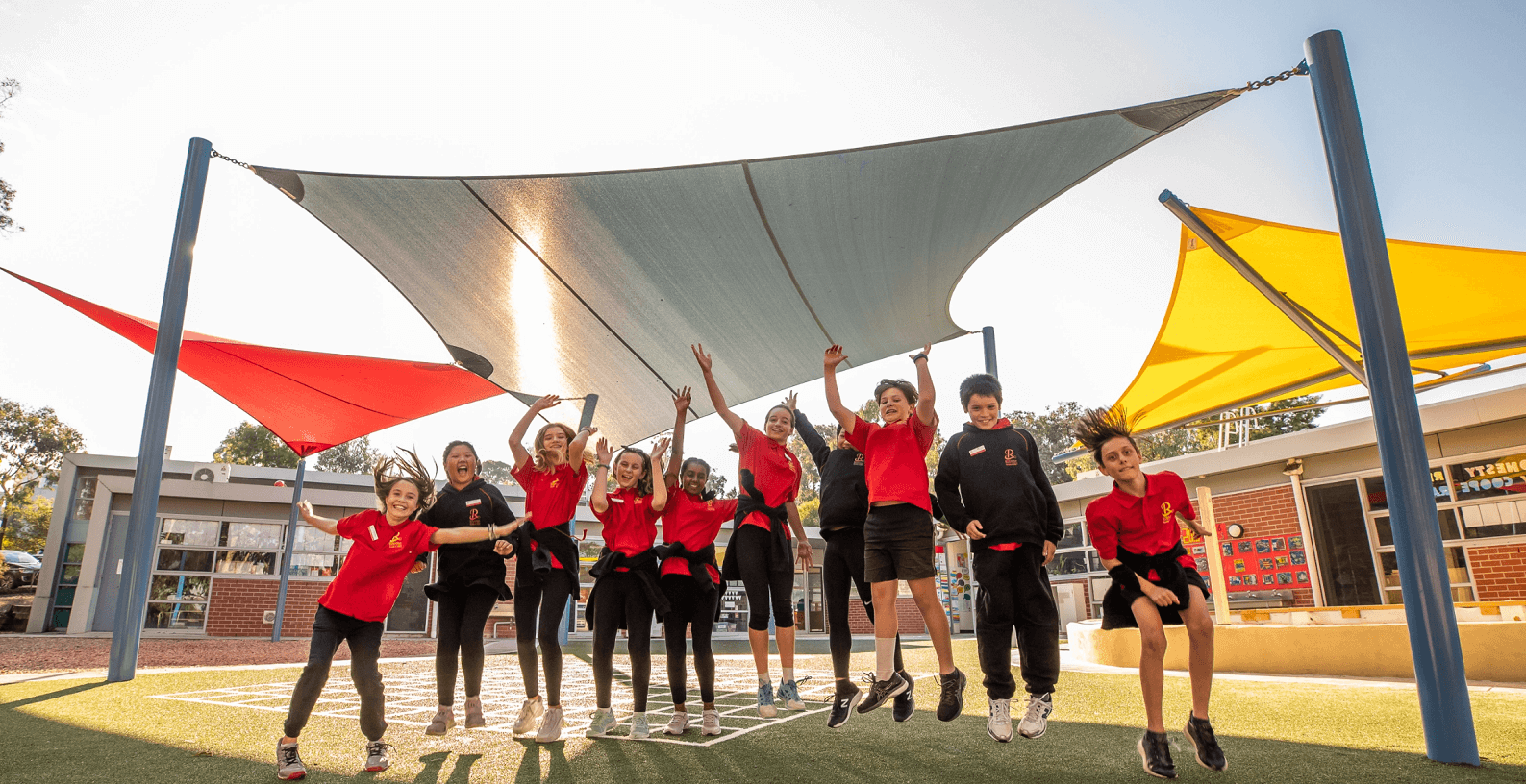 Photo of students celebrating under the shade sails at Rossana Primary school. 