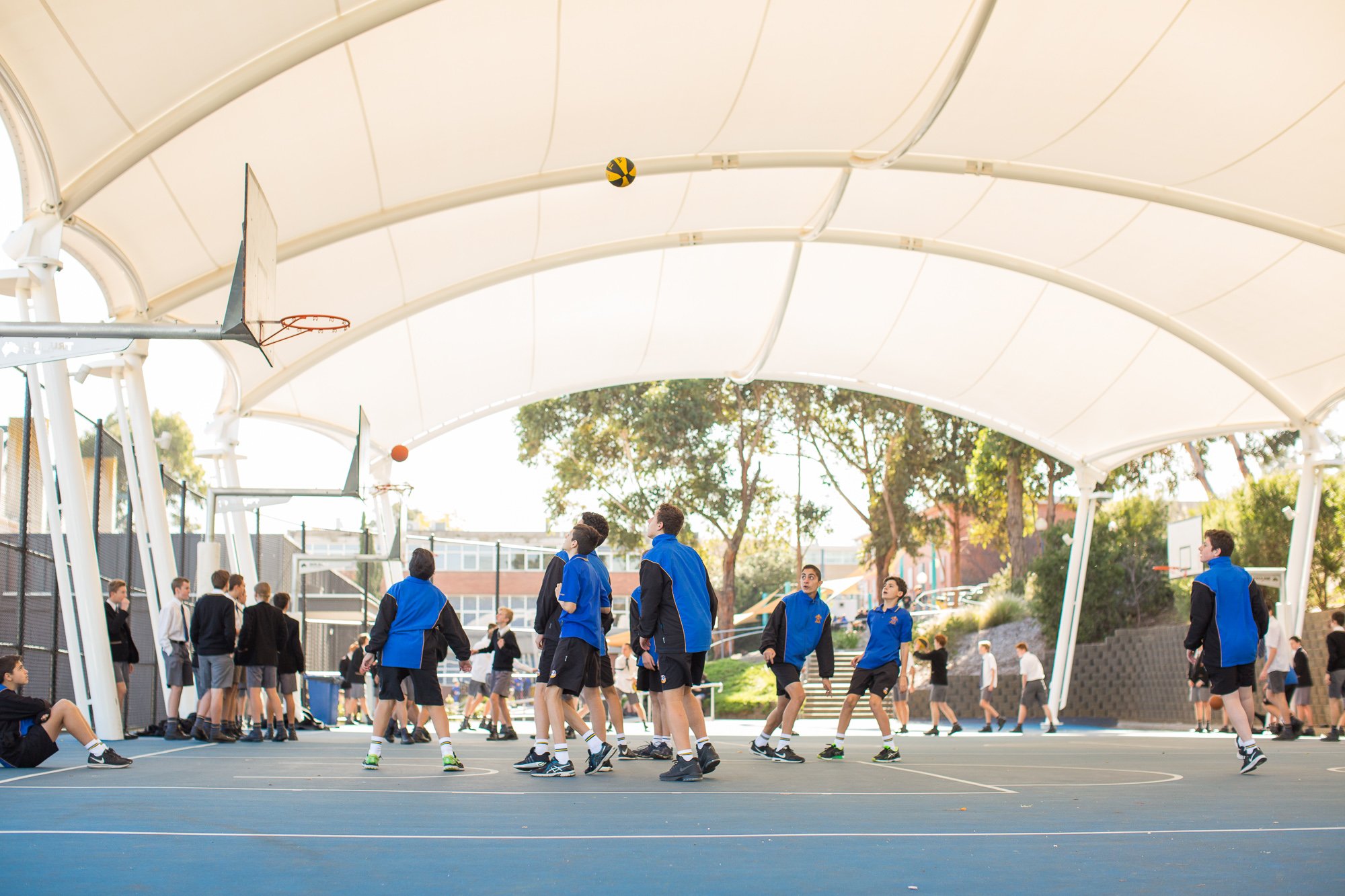 Photo of students playing on the sports courts under the shade cover at St Bernard's College.