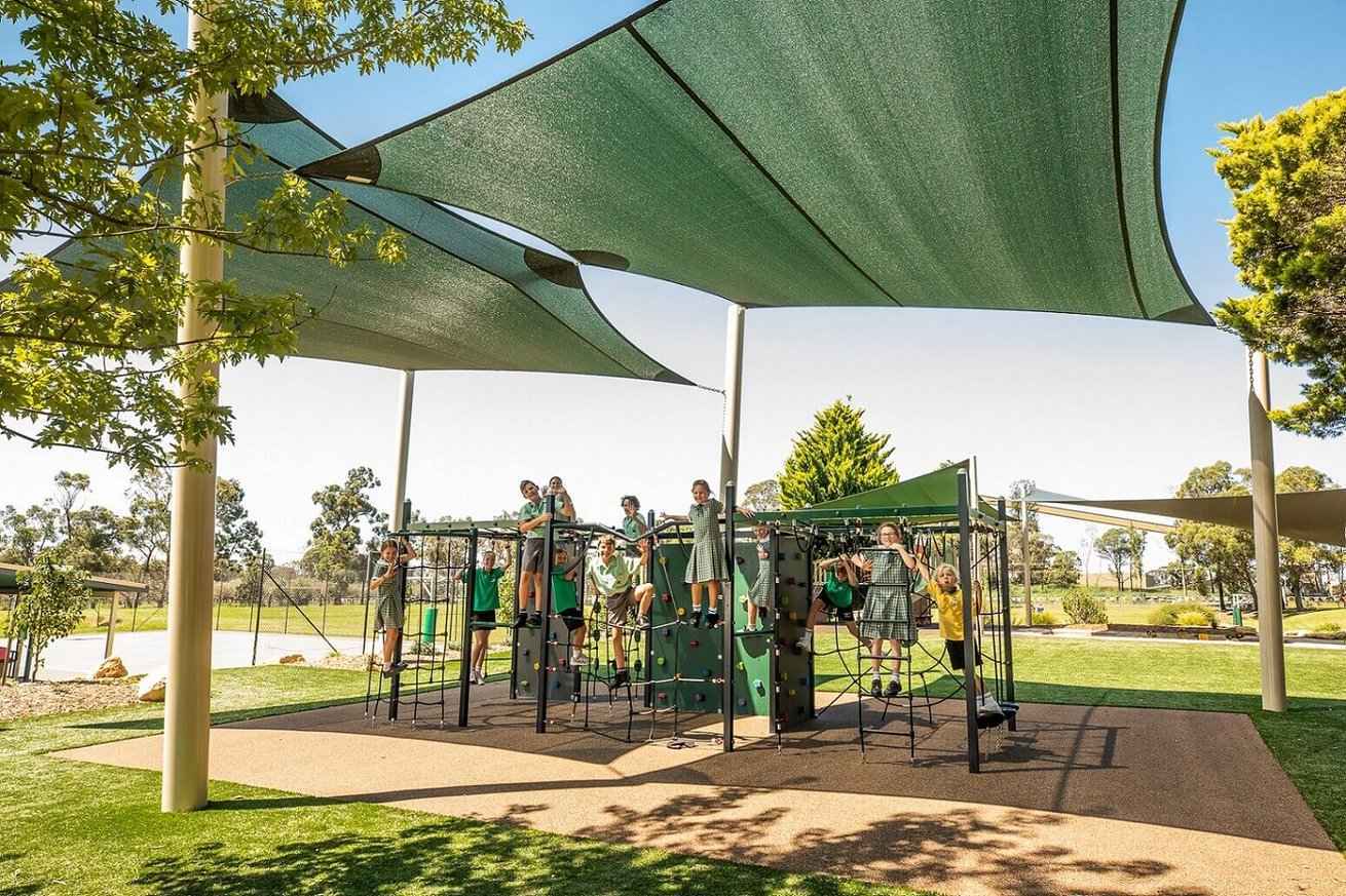 Children playing on school playground under large shade sails.