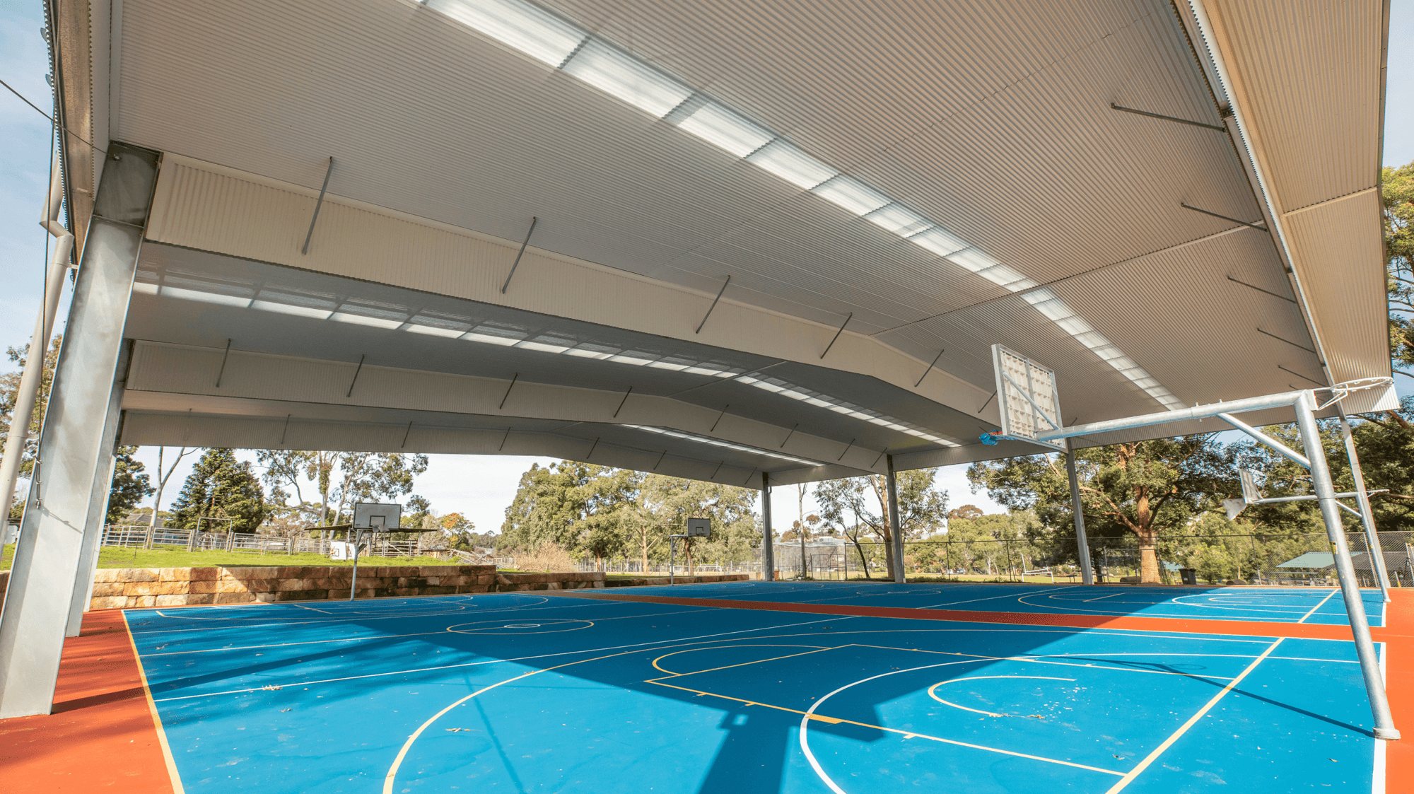 Photo of a metal structure covering basketball courts. 