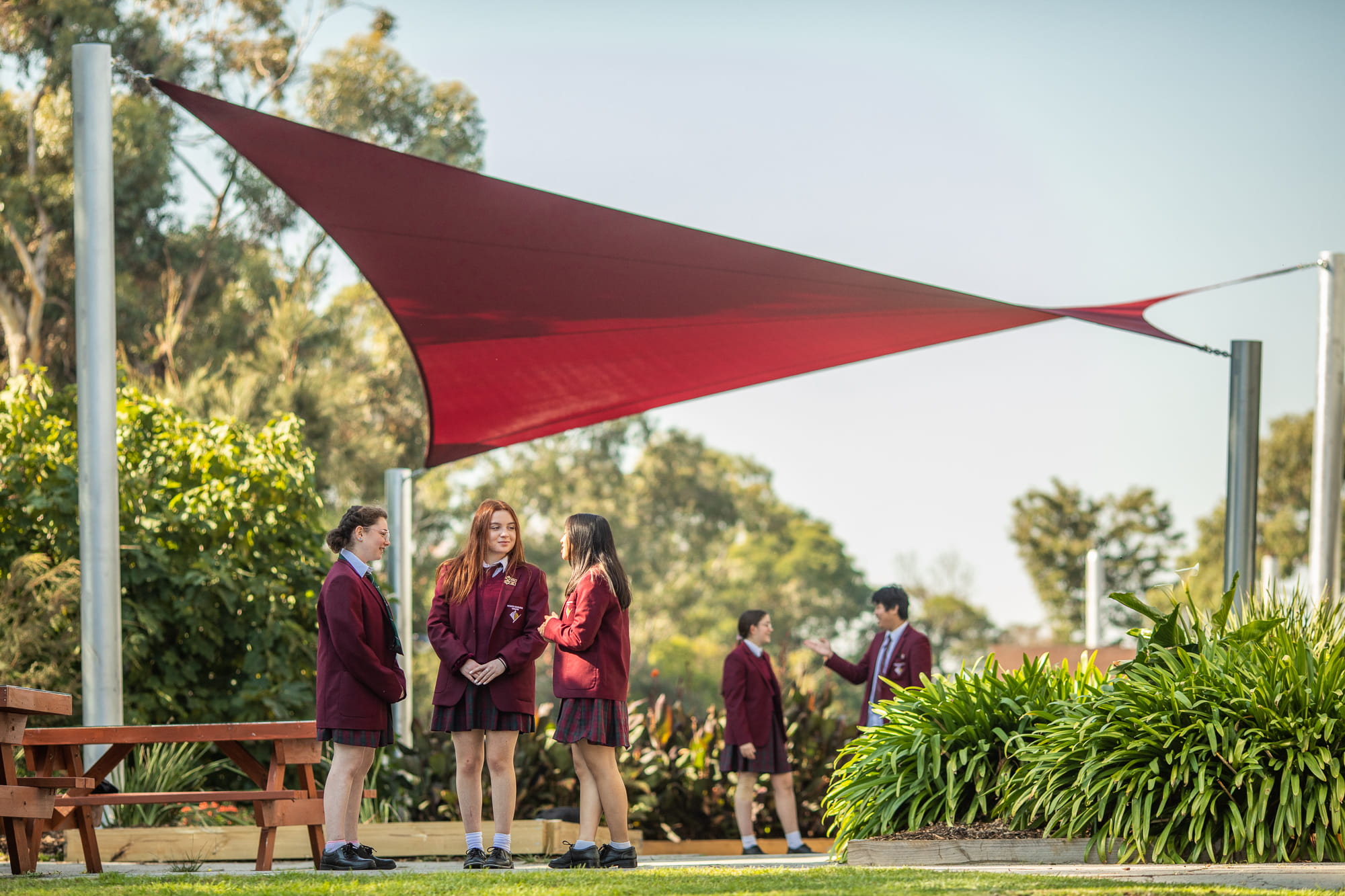 Photo of students standing nearby the shade sails of a high school. 